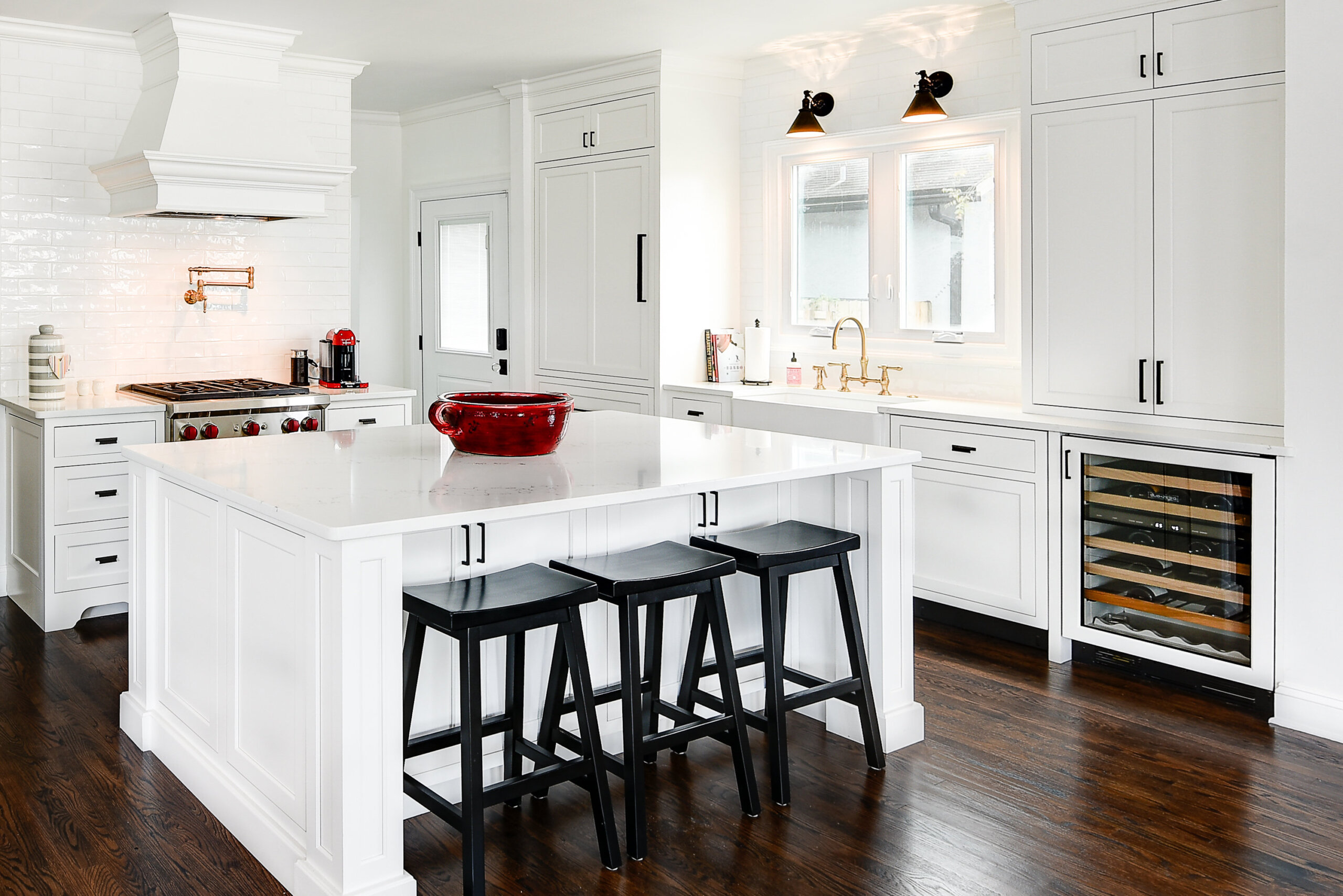 A bright white kitchen with a large kitchen island and wood hood.
